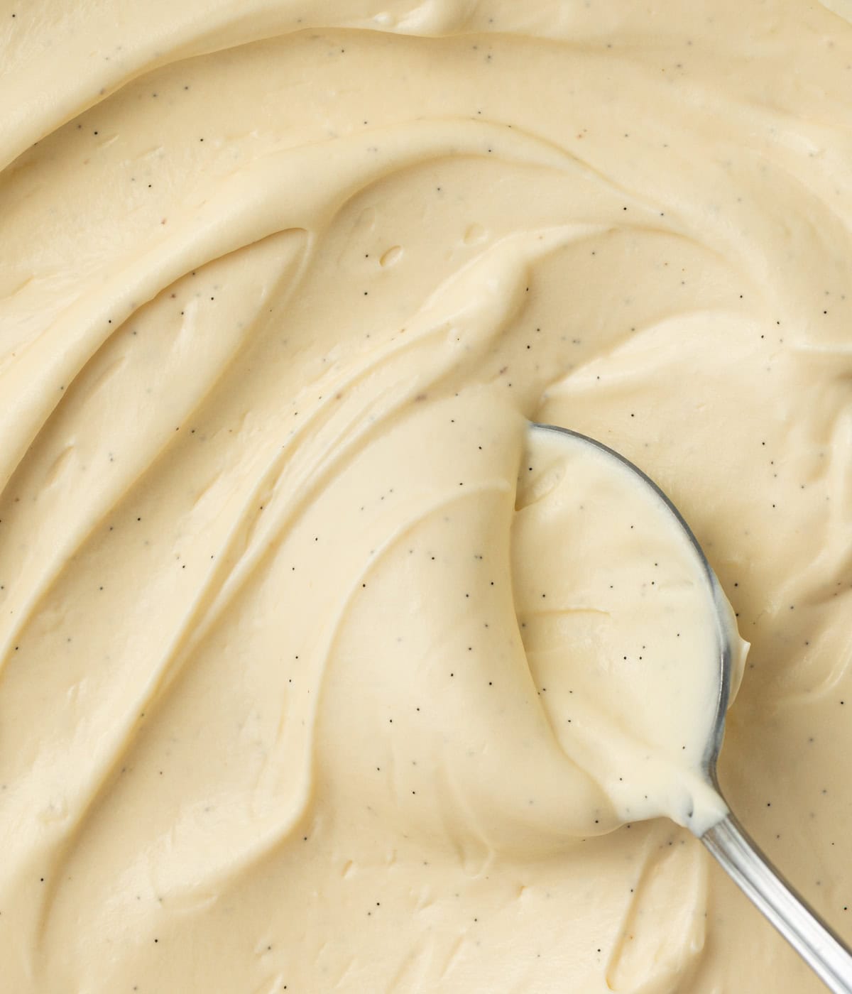 Close up on the cream swirled in a bowl with a spoon, seen from above.