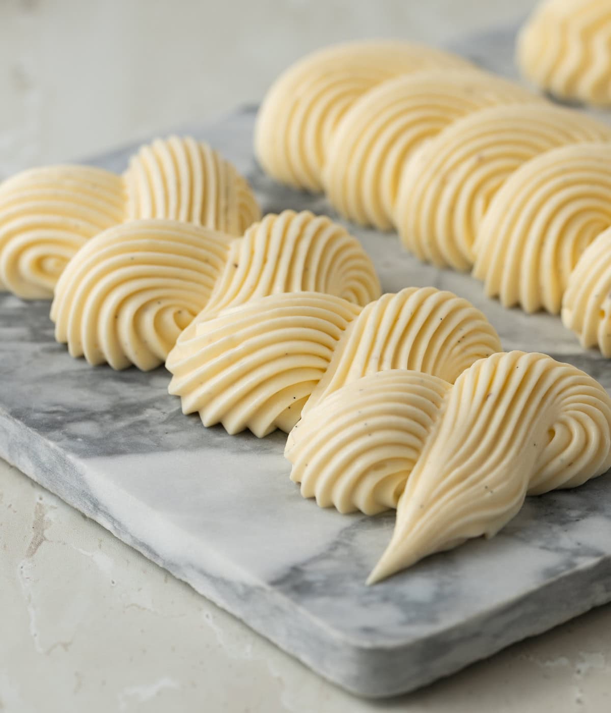 Cream piped in a swirl line over a marble plate.