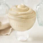 Swirls of creme legere piped inside a small glass cup.