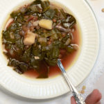 lemon lentil soup in a white bowl with a spoon held by a hand