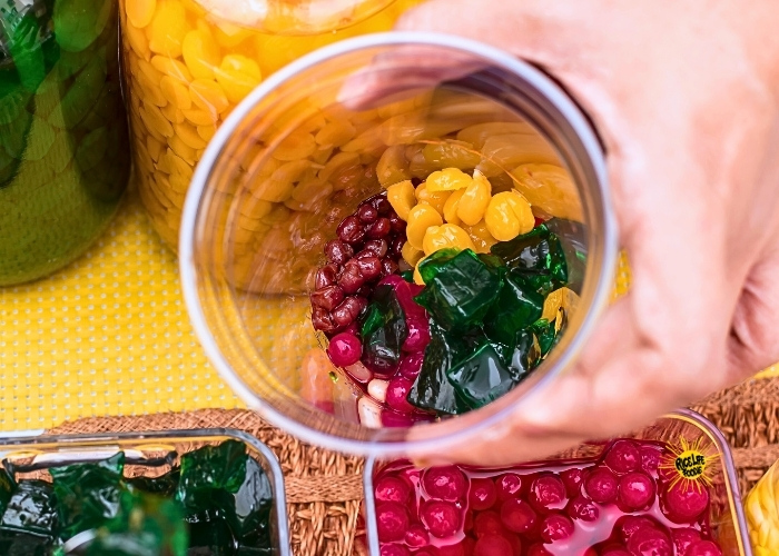 adding halo halo ingredients to a plastic cup