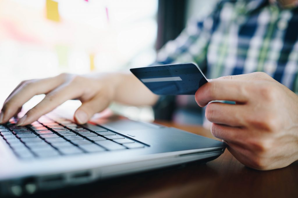 man holds credit card and uses laptop