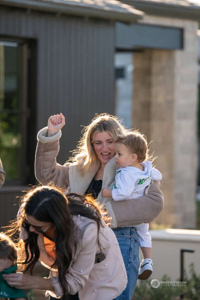 Event Photography for an Unforgettable First Birthday 21 This is an image of a lady holding a child who is celebrating his first birthday. She is looking at him throwing her had in the air and celebrating with him.
