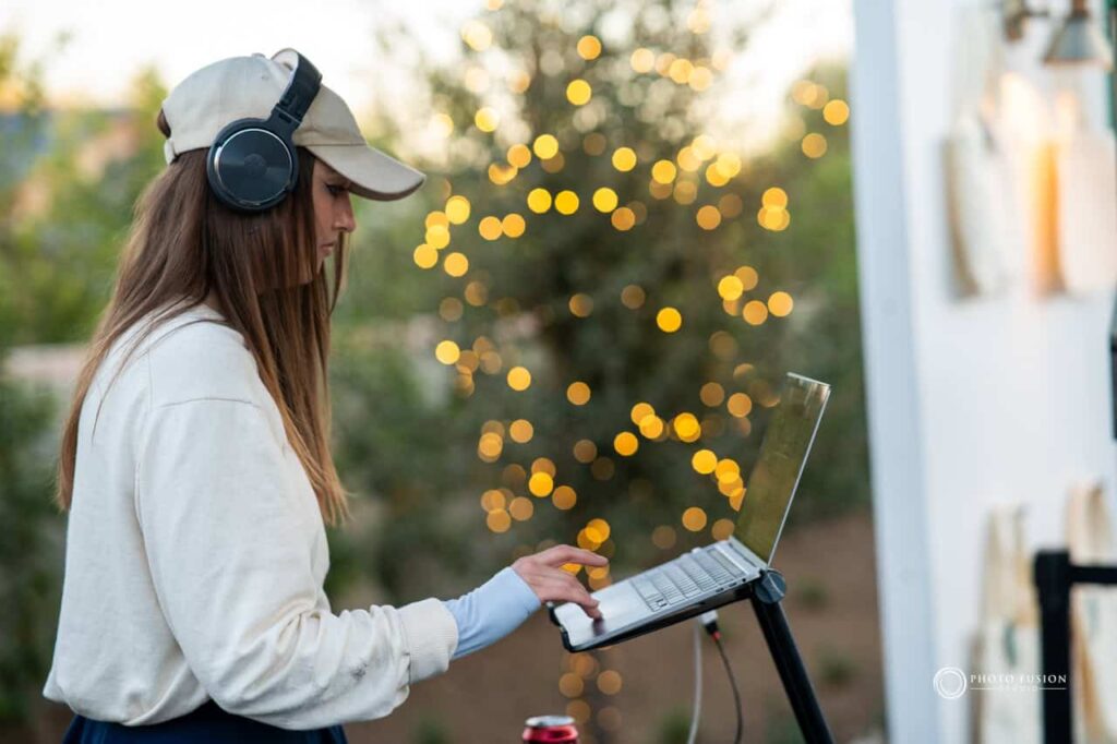 Event Photography for an Unforgettable First Birthday 42 DJ is set up outside at a one year olds birthday party that is masters golf theme. She is wearing headphones and has a laptop in front of her that she is using to DJ.