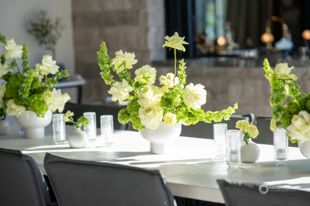 Event Photography for an Unforgettable First Birthday 19 Image of floarl decorations that are sitting on a table. There is a big white pot and white flowers coming out of the pot along with greenary.