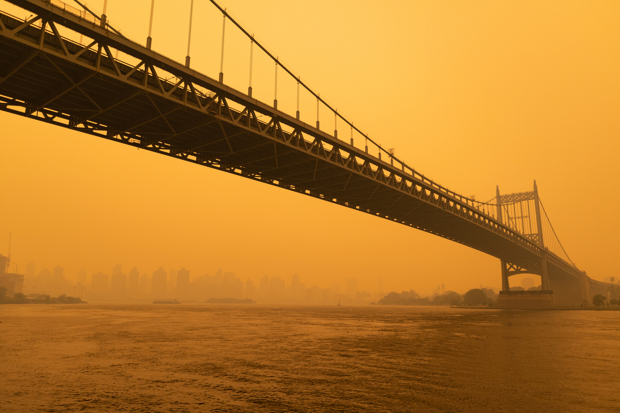 Orange smoke surrounds a New York City bridge.