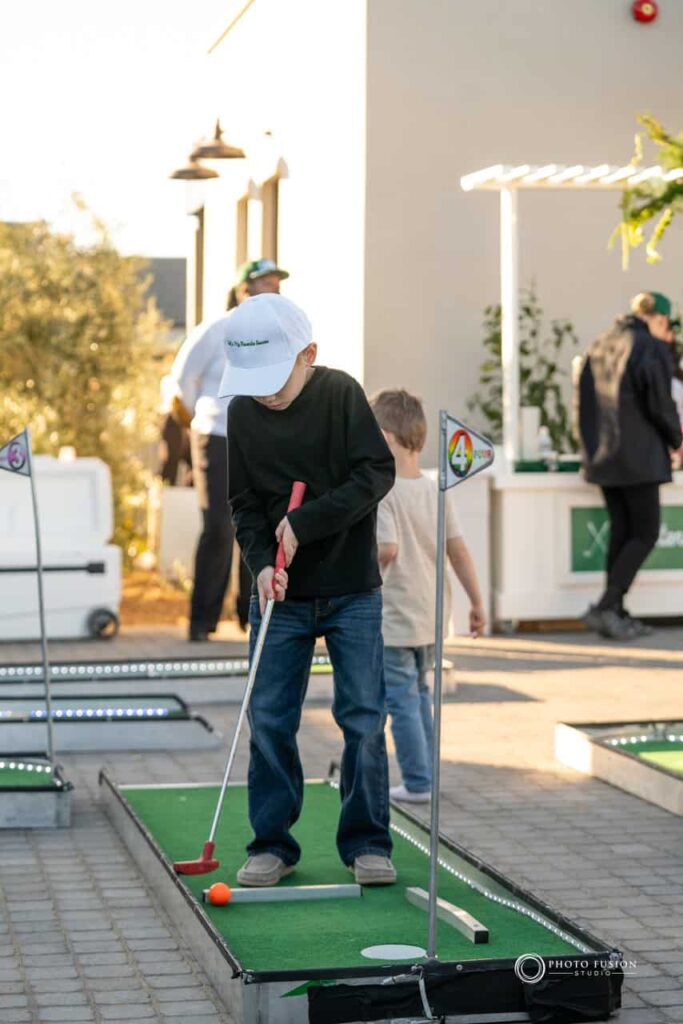 Event Photography for an Unforgettable First Birthday 9 Child playing mini golf at a one year olds birthday party. He is on hold number 4 of the mini golf.