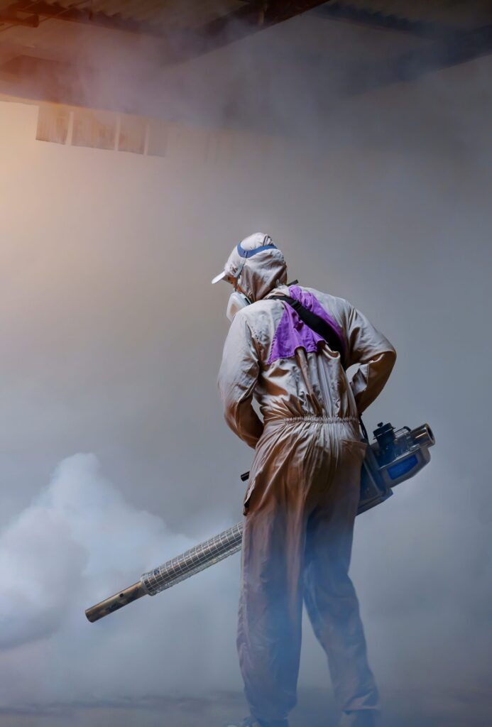 An exterminator in protective clothing fumigates a severely infested property