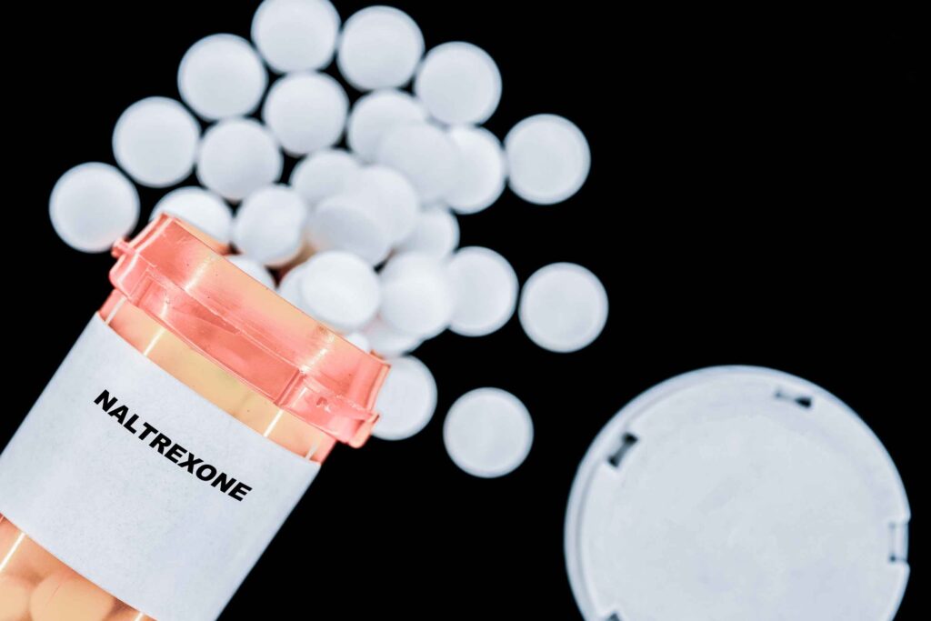 An orange pharmacy bottle of naltrexone is spilled over representing the medication used in the Sinclair Method for Alcohol.