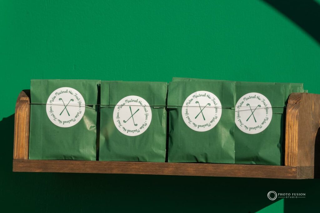 Event Photography for an Unforgettable First Birthday 12 Up close shot of snacks that are on a shelf hanging on a wall. They are in green packaging and the sticker has two golf clubs in the center, the words around it say mateo mastered his first year.
