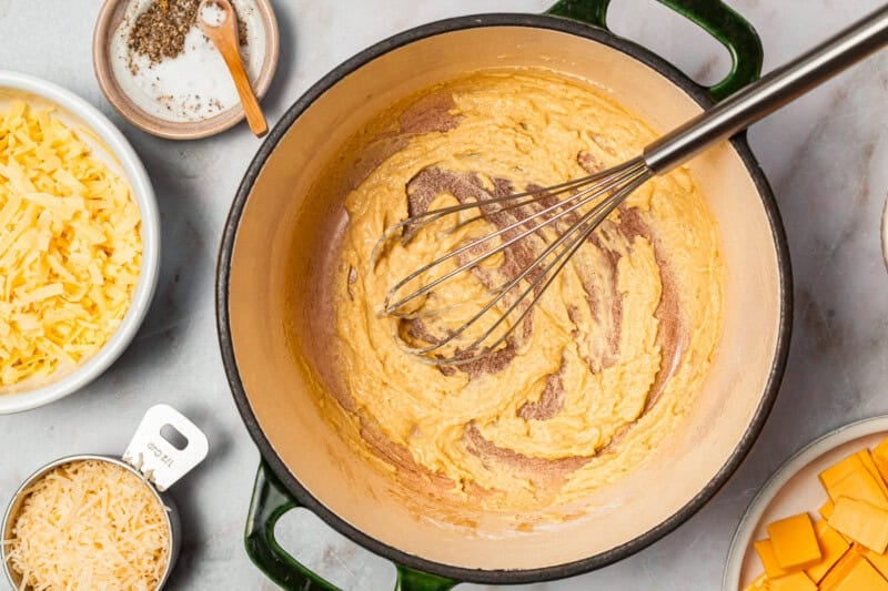 whisking a roux in a dutch oven with a whisk.