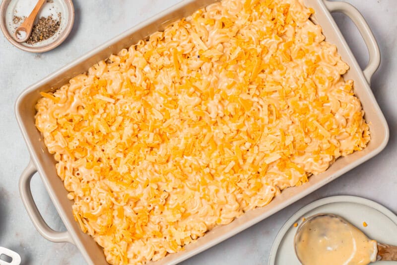 shredded cheese sprinkled over chick fil a mac and cheese in a casserole dish.