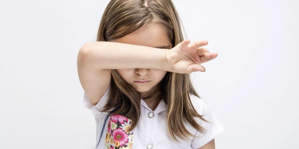 Young girl shielding her face with her arm, symbolizing the emotional impact and need for a temporary protection order