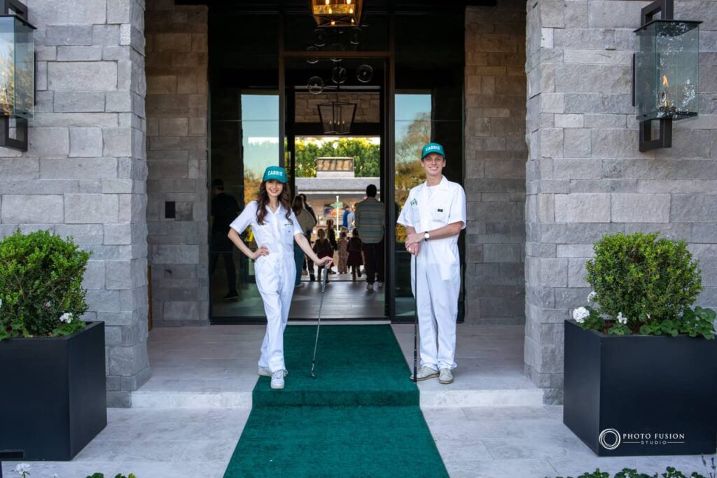Event Photography for an Unforgettable First Birthday 4 There are two people one on the left who is a female and one on the right who is a male. They are both wearing white caddie outfits and green hats that say caddie on them. They also both have a golf club that they are holding.
