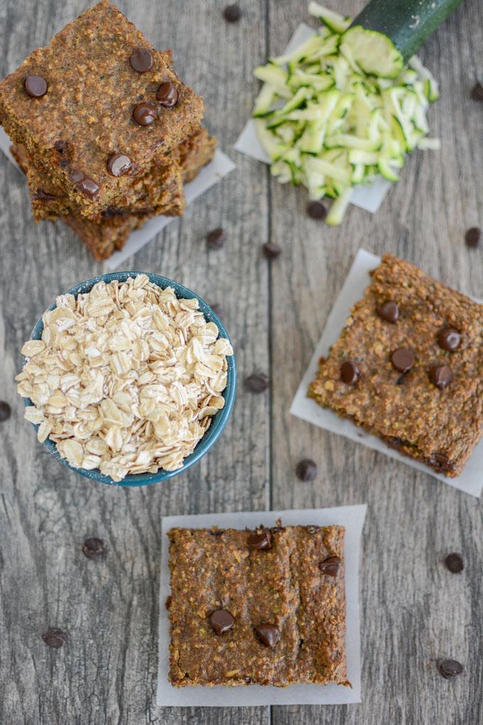 Zucchini Oatmeal Chocolate Chip Bars 3 overhead shot of zucchini oat bars with bowl of oats and shredded zucchini